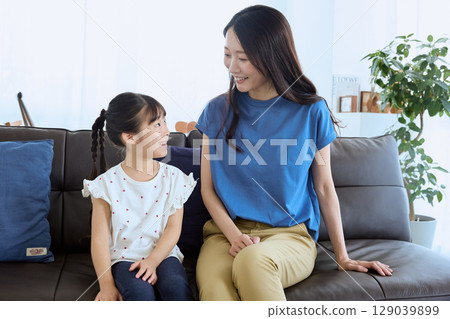 Mother and daughter having a fun conversation in the living room – Homely 129039899