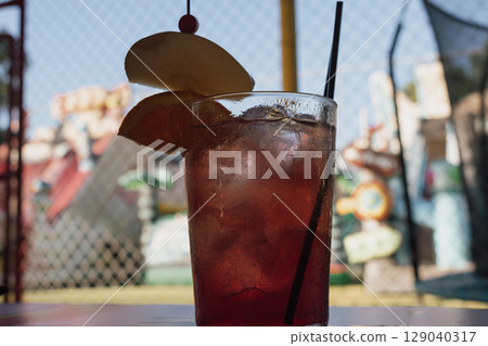 Strawberry mojito on the table with orange and apple, children's playground in the background Strawberry mojito on the table with orange and apple, children's playground in the background 129040317