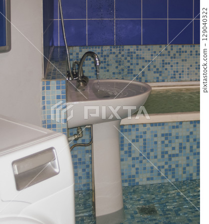 Flooding in a bathroom. Someone left the faucet open and water is overflowing, flooding the room 129040322