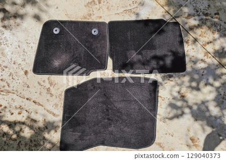 Black car mats drying after being washed on asphalt in the yard 129040373