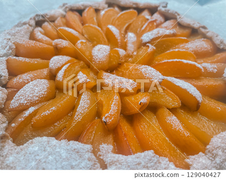 Delicious galette with bright juicy orange apricot slices generously dusted with powdered sugar Delicious galette with bright juicy orange apricot slices generously dusted with powdered sugar 129040427