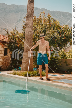 Happy young man cleaning his own pool in Greek nature Happy young man cleaning his own pool in Greek nature 129040554