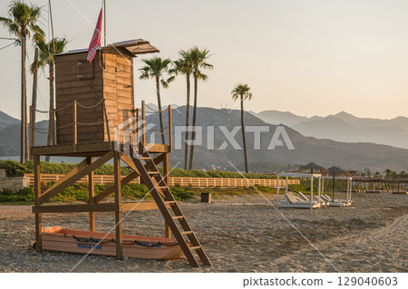 Lifeguard hut on a Greek beach, rescue boat underneath, palm trees and beautiful landscape of Crete 129040603