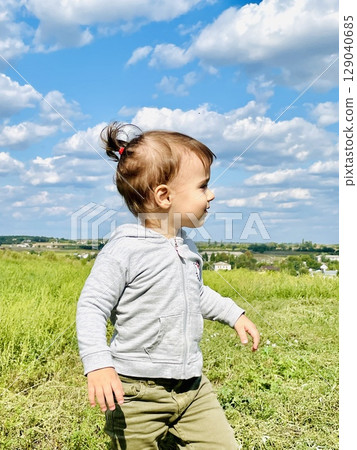 Little girl running through a field with tall grass 129040685