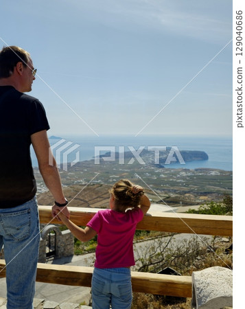 Father and daughter enjoying the view from the highest point of Santorini island 129040686