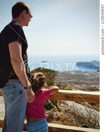 Father and daughter enjoying the view from the highest point of Santorini island 129040697