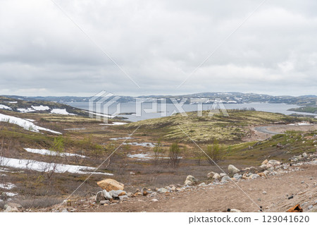 Scenic Arctic tundra landscape near Teriberka, Russia, with moss-covered hills, small lakes, and piles of stones under dramatic cloudy skies Scenic Arctic tundra landscape near Teriberka, Russia, with moss-covered hills, small lakes, and piles of stones under dramatic cloudy skies 129041620