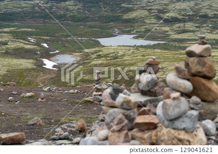 Stone cairns stacked on the tundra overlook a winding river and moss-covered hills near Teriberka, Russia Stone cairns stacked on the tundra overlook a winding river and moss-covered hills near Teriberka, Russia 129041621