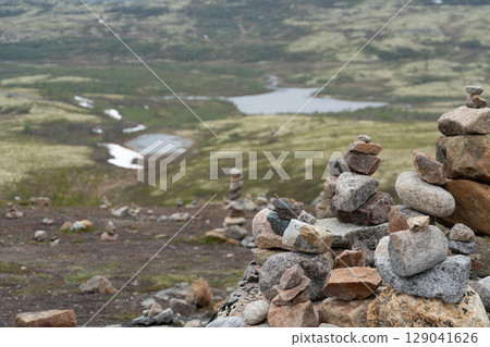 Stone cairns stacked on the tundra overlook a winding river and moss-covered hills near Teriberka, Russia Stone cairns stacked on the tundra overlook a winding river and moss-covered hills near Teriberka, Russia 129041626