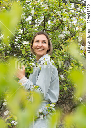 Smiling middle-aged woman in a light blue outfit. Natural cosmetics, wellness retreats, and mental health awareness Smiling middle-aged woman in a light blue outfit. Natural cosmetics, wellness retreats, and mental health awareness 129041880