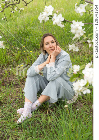 Close-up of a woman in a pastel blue outfit adjusting delicate white lace socks. Feminine detail ideal for lingerie branding, slow fashion promotion, and wellness-related content 129041954
