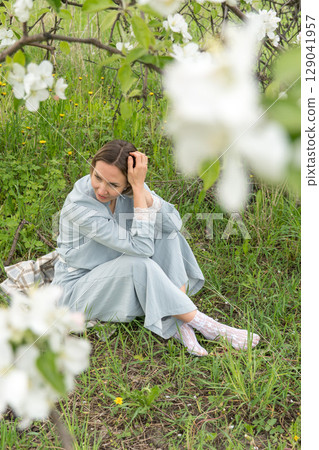 Close-up of a woman in a pastel blue outfit adjusting delicate white lace socks. Feminine detail ideal for lingerie branding, slow fashion promotion, and wellness-related content 129041957