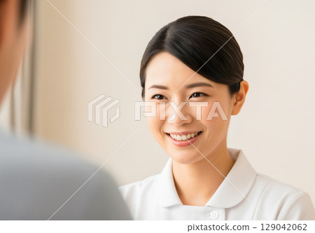 A female nurse smiling and talking to a patient 129042062