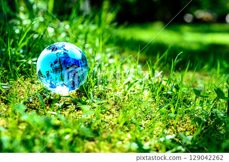 A crystal globe in a field of grass. Ecological image. Blue. 129042262