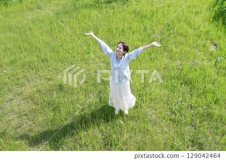 Aerial view of a woman taking a deep breath in the field Aerial view of a woman taking a deep breath in the field 129042464