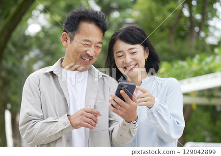 Middle-aged couple using smartphone outdoors 129042899