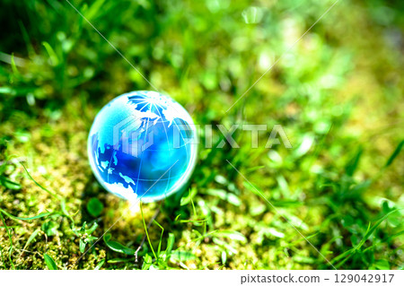 A beautiful globe crystal in a field of grass. Ecological image. Blue. 129042917