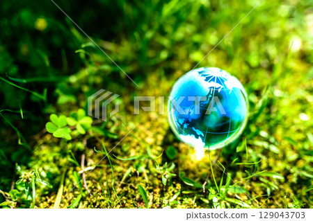 Beautiful globe crystal in a field of grass. Ecological image. Blue daytime. 129043703