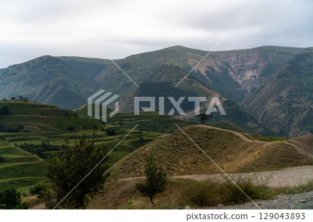 A mountain range with a cloudy sky in the background A mountain range with a cloudy sky in the background 129043893