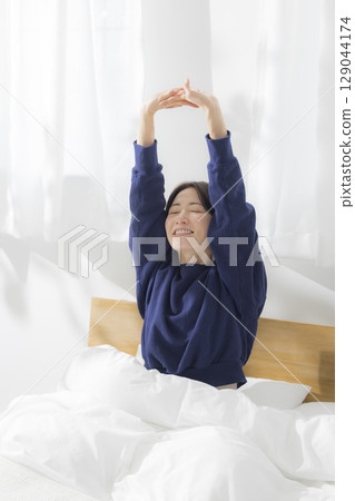 A woman stretching in bed 129044174