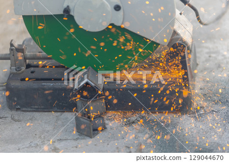 Worker cutting steel rectangular pipe in construction site. Worker cutting steel rectangular pipe in construction site. 129044670
