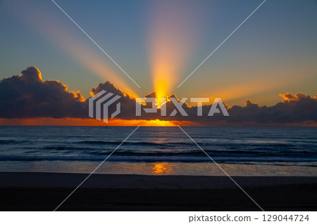A view of the sun rising over the horizon and rays of light from a beach on the Gold Coast in Queensland, Australia A view of the sun rising over the horizon and rays of light from a beach on the Gold Coast in Queensland, Australia 129044724