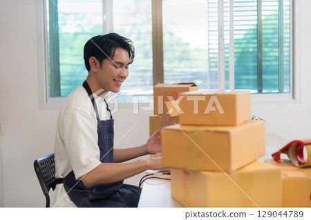 Home Office. Young entrepreneur managing packages and logistics from his desk. 129044789