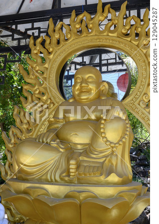 Gilded sculpture of smiling Buddha at Chua Da Bao Monastery 129045287