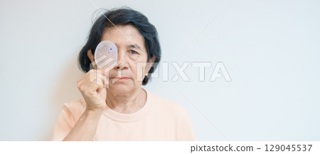 Elderly Woman with eye protective shield after eye surgery. Eye disease, Cataract, Glaucoma, Age Related Macular Degeneration, Diabetic Retinopathy, Vitreous, Lasik, World Glaucoma day and health Elderly Woman with eye protective shield after eye surgery. Eye disease, Cataract, Glaucoma, Age Related Macular Degeneration, Diabetic Retinopathy, Vitreous, Lasik, World Glaucoma day and health 129045537