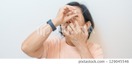 Elderly Woman use ophthalmic solutions or Eye Drops after eye surgery. Eye disease, Cataract,  Glaucoma, Age Related Macular Degeneration, Diabetic Retinopathy, World Glaucoma day and health treatment 129045546