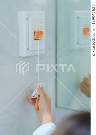 woman Patient hand holding and pulling emergency button in toilet of hospital room, calling nurse in emergency case. Professional Medical system and Safety Alert 129045626