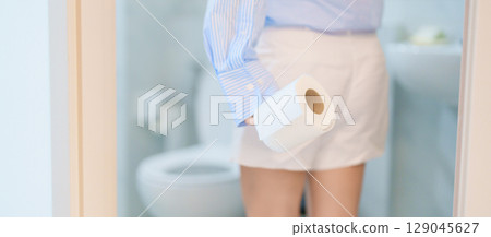 Woman holding toilet paper roll while stand near toilet bowl. digestion, constipation, Diarrhea from food poisoning, infection, abdominal, stomachache, cystitis, Insurance, Health care and Medical 129045627