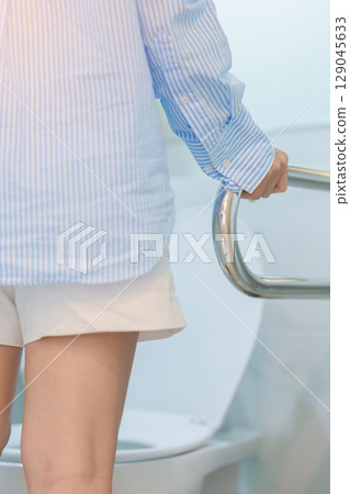Asian elderly woman use toilet support for older in bathroom, female senior hand holding handrail grab bar. Safety and security in nursing hospital or home. Healthcare concept 129045633