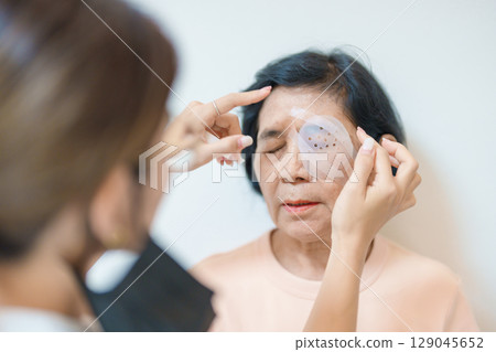 Senior Woman during eye protecting by shield after eye surgery. Eye disease, Cataract, Glaucoma, Age Related Macular Degeneration, Diabetic Retinopathy, Vitreous, Lasik, World Glaucoma day and health Senior Woman during eye protecting by shield after eye surgery. Eye disease, Cataract, Glaucoma, Age Related Macular Degeneration, Diabetic Retinopathy, Vitreous, Lasik, World Glaucoma day and health 129045652