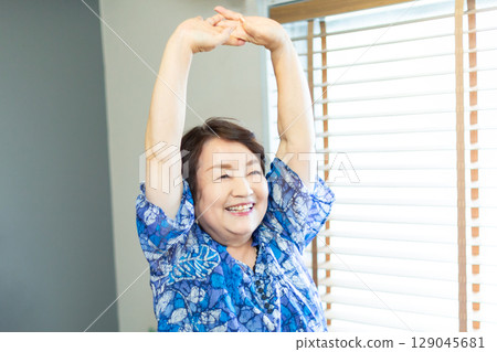 A senior woman in her 60s stretching her arms indoors A senior woman in her 60s stretching her arms indoors 129045681