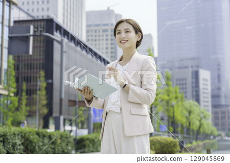 Portrait of a young businesswoman standing with a notebook in an office district 129045869