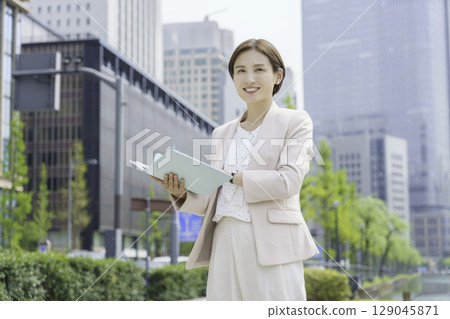 一位年輕女商人站在辦公區拿著筆記本的畫像 129045871