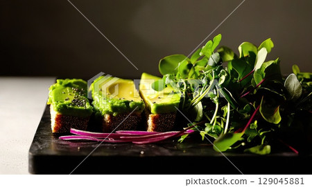 Close-up of fresh avocado toast with microgreens and chia seeds on a dark serving slate 129045881