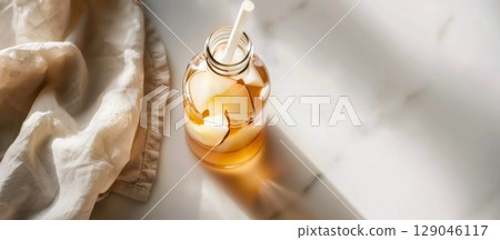 Detailed glass bottle of kombucha with fruit slices and straw on a pristine white background Detailed glass bottle of kombucha with fruit slices and straw on a pristine white background 129046117