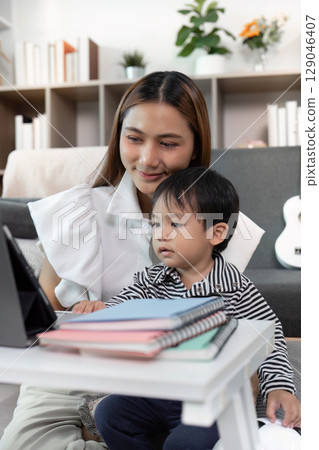 Focused Learning. Child Watching Tablet with Mother in Cozy Living Room Focused Learning. Child Watching Tablet with Mother in Cozy Living Room 129046407