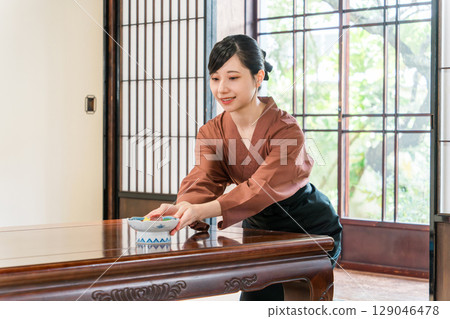 一位女服務生正在為旅館的客房提供食物，一位旅館工作人員 129046478