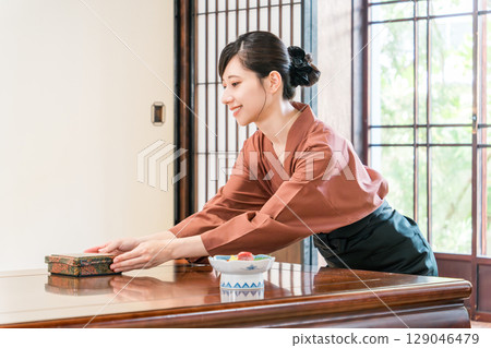 A waitress serving food to the guest rooms of an inn, a ryokan staff member A waitress serving food to the guest rooms of an inn, a ryokan staff member 129046479