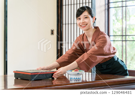 一位女服務生正在為旅館的客房提供食物，一位旅館工作人員 129046481