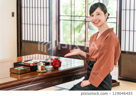 A waitress serving food to the guest rooms of an inn, a ryokan staff member 129046485