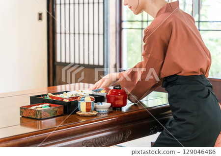 A waitress serving food to the guest rooms of an inn, a ryokan staff member A waitress serving food to the guest rooms of an inn, a ryokan staff member 129046486