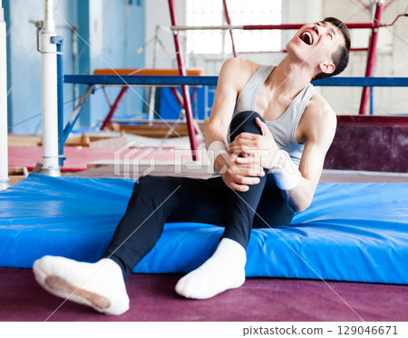Injured male gymnast suffering from knee pain after bad landing 129046671