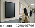 Female students walking down a school corridor with a large digital signage installed on the wall 129046796