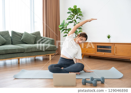 Young Asian woman stretching yoga workout on exercise mat 129046898