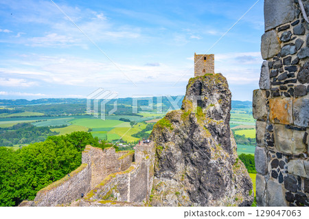 Trosky Castle Ruins rise majestically amidst the lush Bohemian Paradise landscape in Czechia. Visitors enjoy panoramic views of the surrounding hills and valleys on a clear day. 129047063