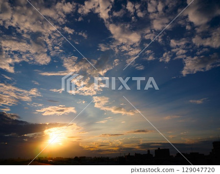 Crepuscular rays stretching through gaps in the clouds at sunset 129047720